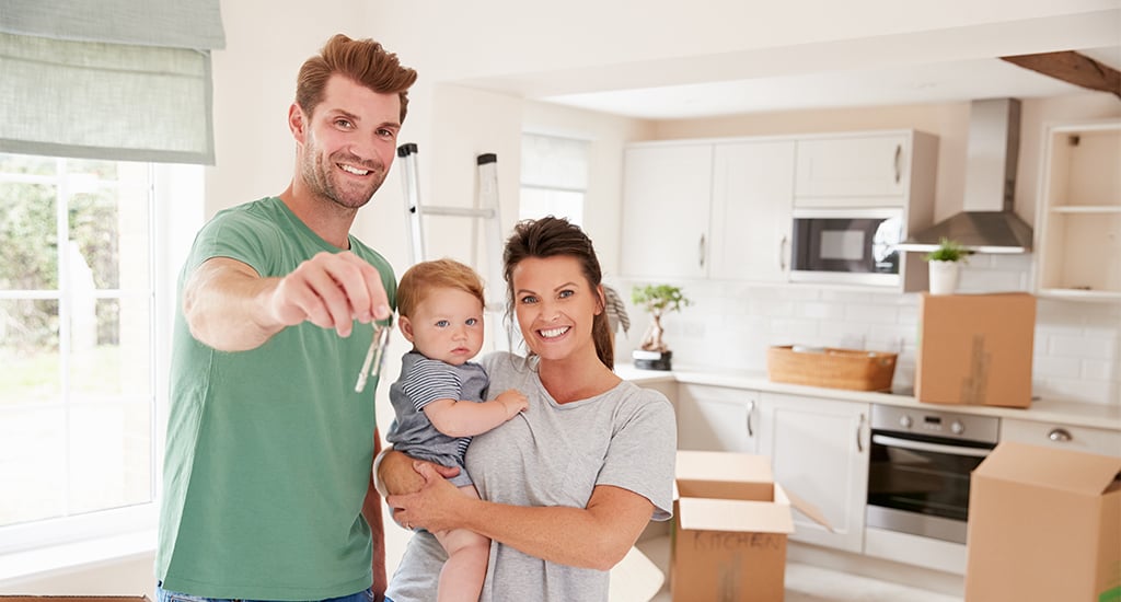Portrait Of Family With Baby Holding Keys On Moving In Day