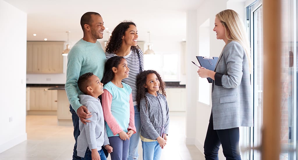 Female Realtor Showing Family Interested In Buying Around House